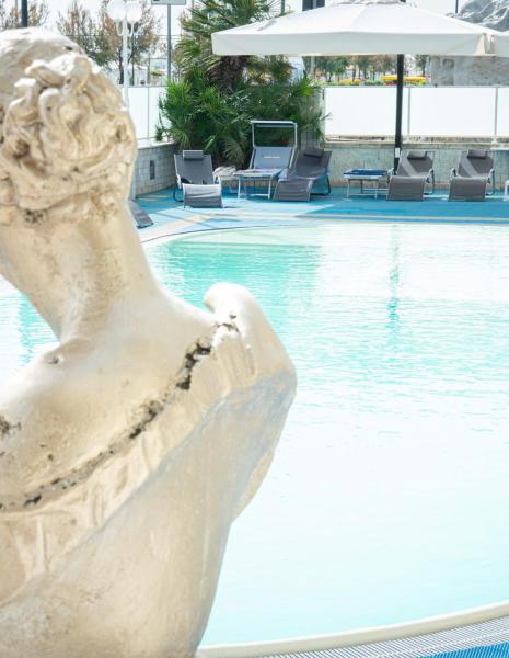 Piscina con statue e lettini, ambiente rilassante.