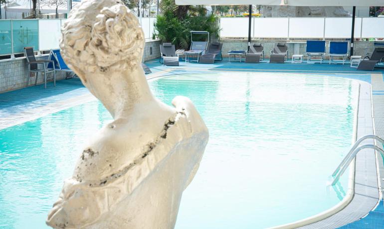 Piscina con statue e lettini, ambiente rilassante.