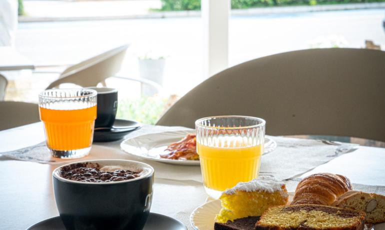Colazione con caffè, succo d'arancia e dolci su un tavolo.