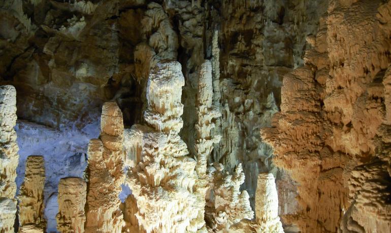 Stalattiti e stalagmiti in una caverna illuminata.