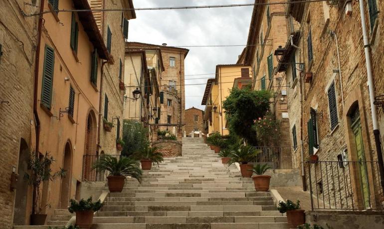 Scalinata tra edifici storici con vasi di fiori.