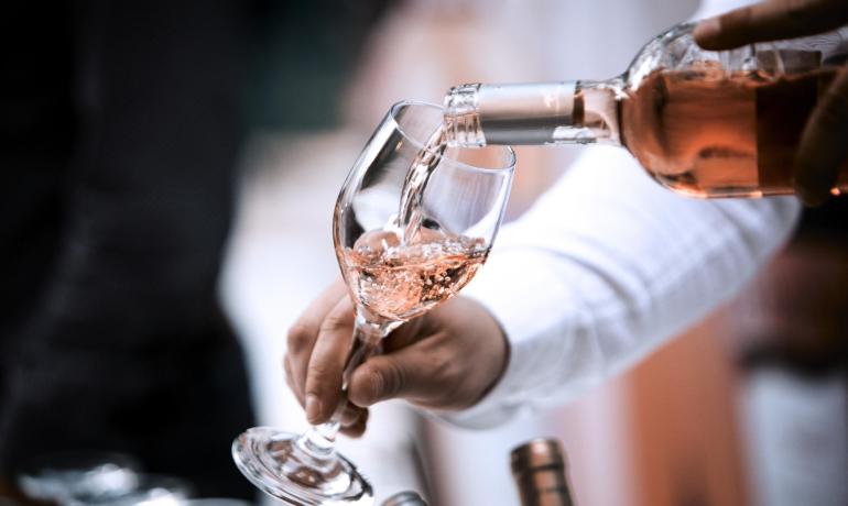 Vino rosato versato in un bicchiere da una bottiglia.