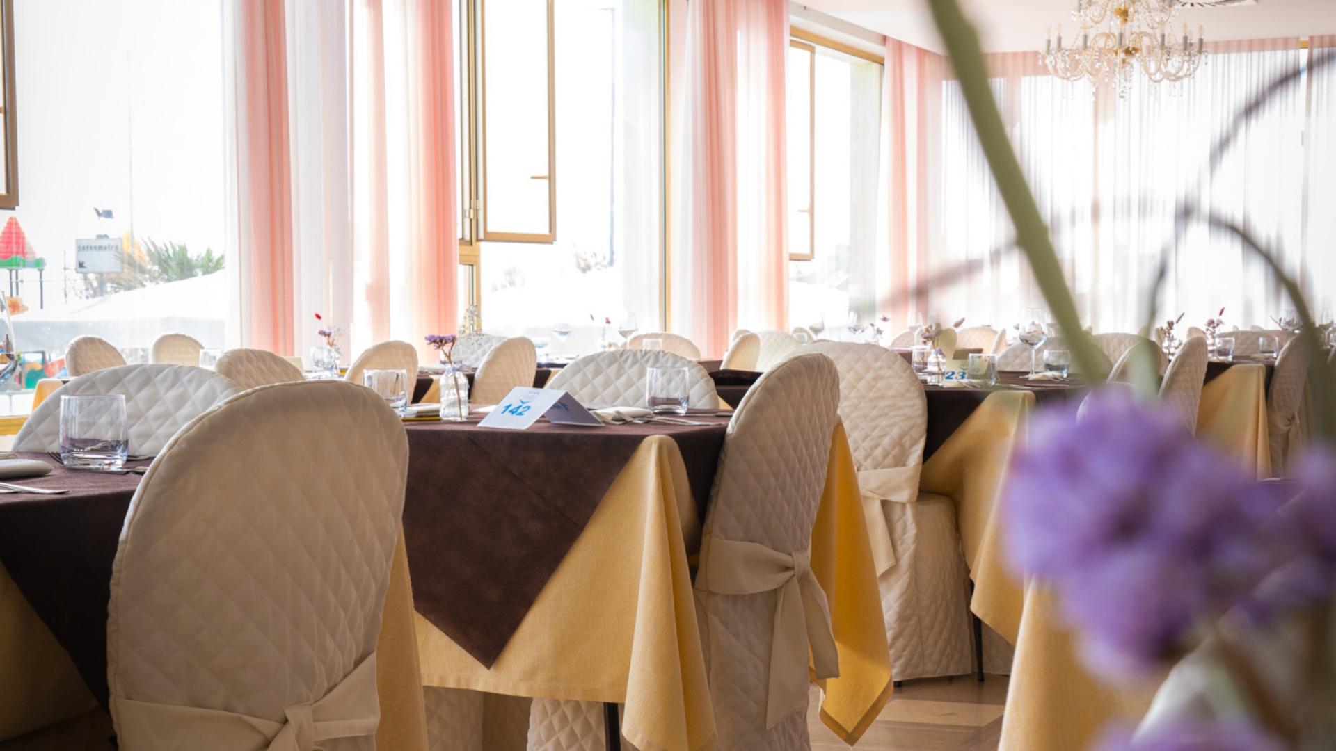 Elegant restaurant with colorful tablecloths and covered chairs.