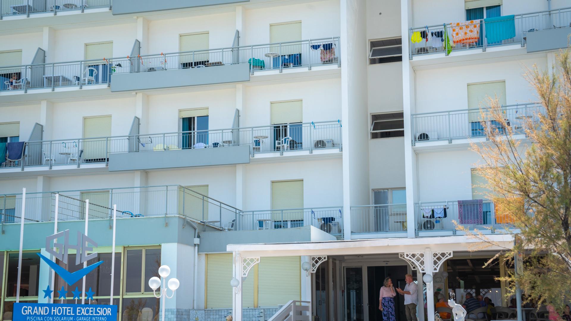Hotel facade with balconies and people at the entrance.