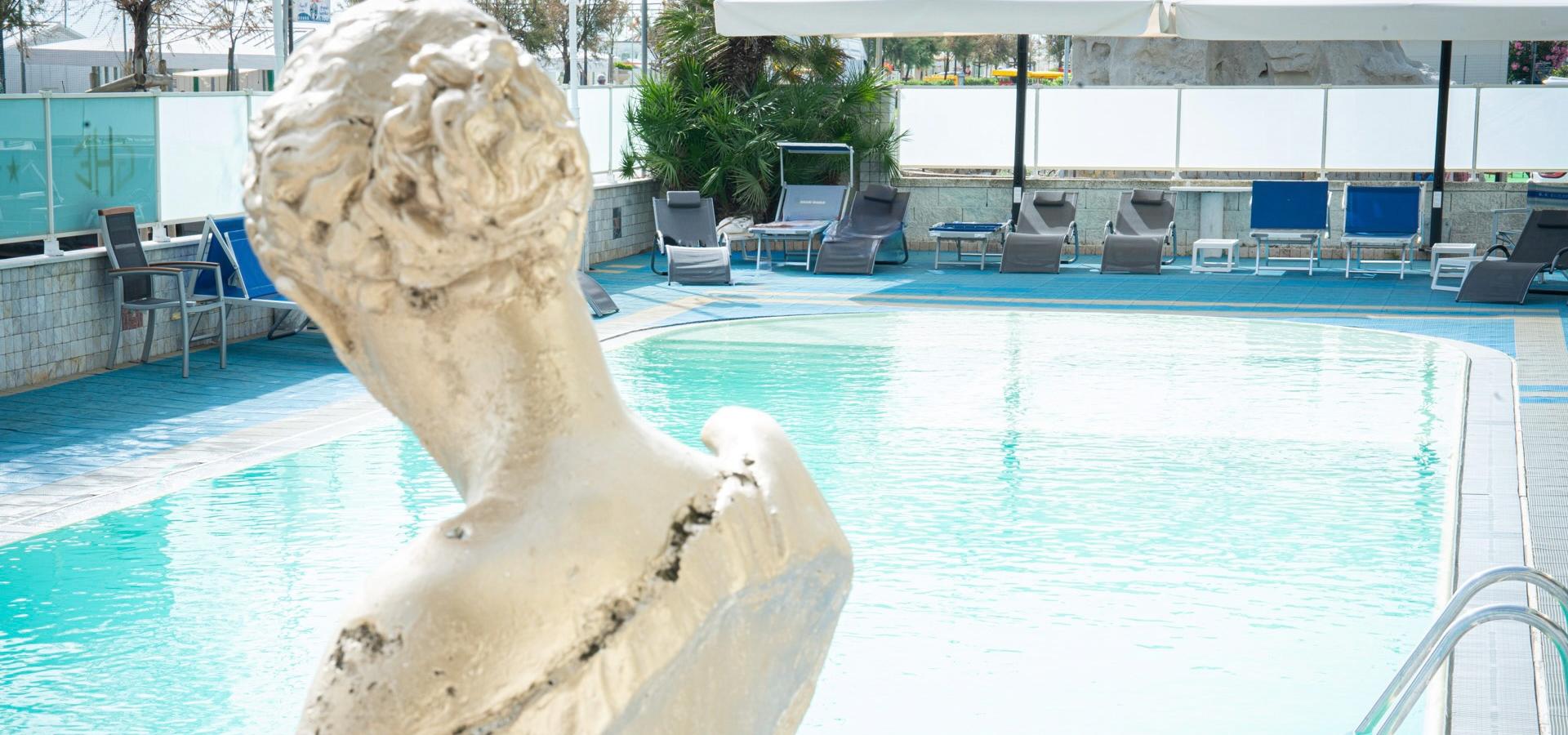 Outdoor pool with statues and loungers.