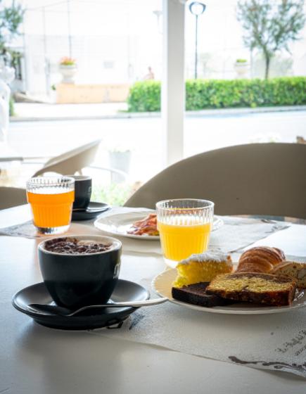 Colazione con caffè, succo e dolci su un tavolo all'aperto.