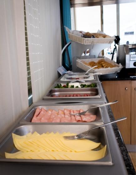 Buffet with cheese, cold cuts, and bread in a hotel.