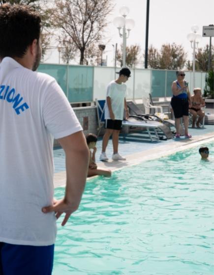 Lifeguard watches pool, people relax poolside.