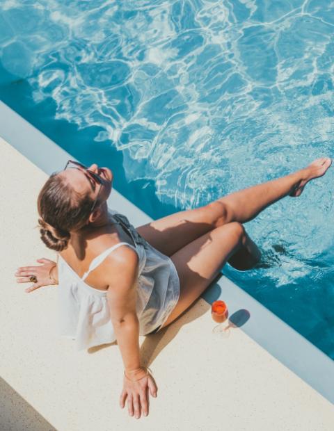 Woman relaxing by the pool with a drink.