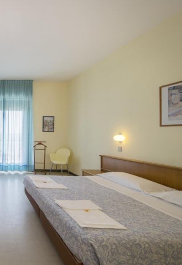 Camera luminosa con letto matrimoniale e arredi semplici.
