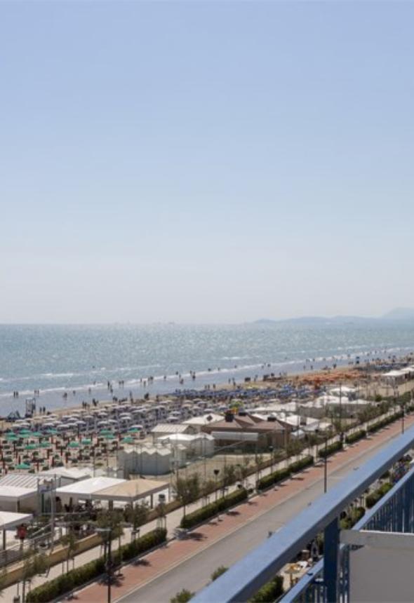 Spiaggia affollata con ombrelloni colorati e mare scintillante.