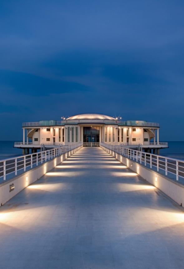 Modern building on a lit pier at dusk.